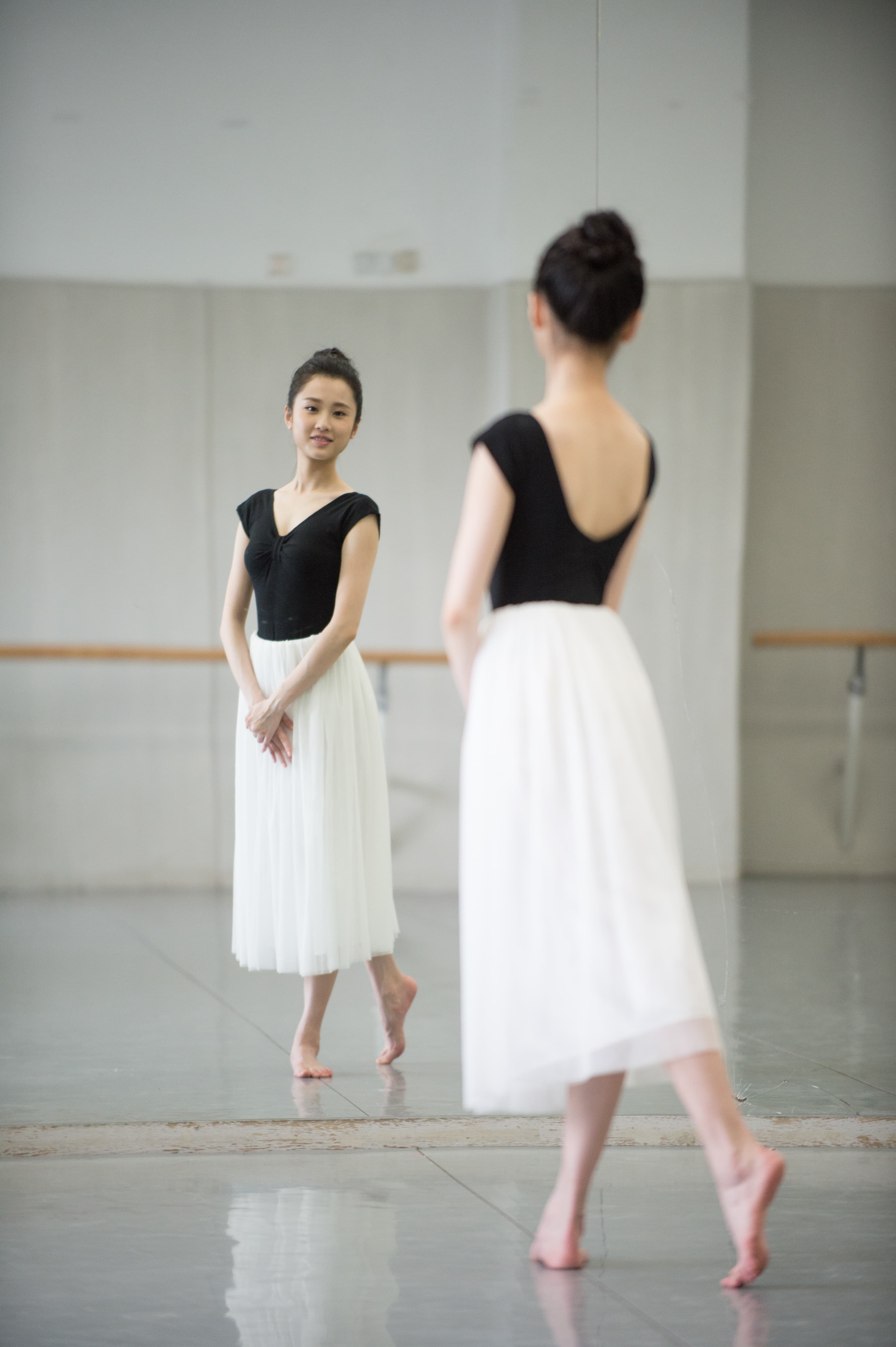 Close-up of dancer's feet and ankles, stocking seams and gentle toe curl visible against floorboards
